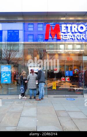 Metro Bank-Schaufenster oder -Fassade, Market Street, Manchester City Centre. Drei Personen nutzen einen geldautomaten. Dezember 2020 Stockfoto