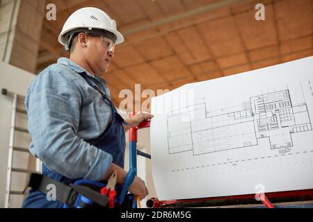 Niedrig Winkel Porträt der weiblichen Ingenieur Inspektion Grundrisse während Arbeiten auf der Baustelle Stockfoto