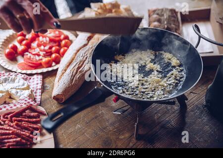 Bratzwiebel für Rühreier in den Bergen. Tourist Frau bereitet köstliche touristische Frühstück im Freien. Stockfoto