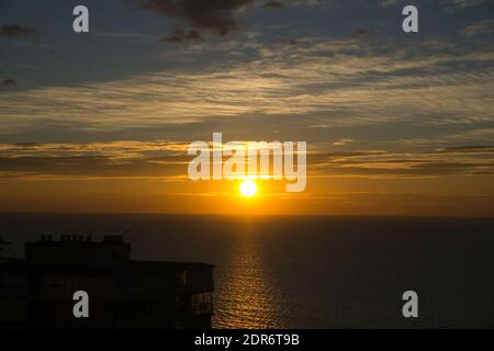 Schöner Sonnenaufgang am Meer von der Stadt aus gesehen mit Wolken Stockfoto