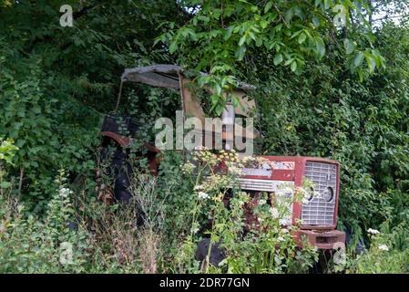 Alter Traktor auf Bauernhof in Frankreich überwuchert Stockfoto