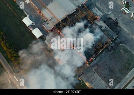 Luftaufnahme eines brennenden Industriegebäudes, Brand mit großem Rauch vom verbrannten Dach. Stockfoto