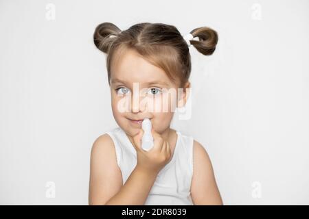 Rissige und trockene Lippen, Promo von feuchtigkeitsspendenden Lippenbalsam. Nahaufnahme Porträt von kleinen Mädchen in weiß oben, Anwendung hygienischen Lippenstift Balsam auf ihre Lippen Stockfoto