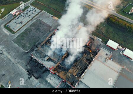 Luftaufnahme eines brennenden Industriegebäudes, Brand mit großem Rauch vom verbrannten Dach. Stockfoto