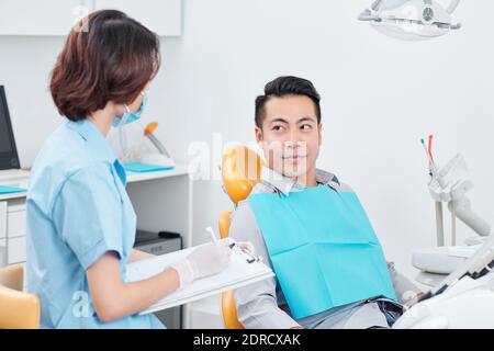 Krankenschwester, die mit dem Patienten im Zahnstuhl spricht Stockfoto