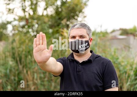 Junger Mann in schützender Gesichtsmaske. Panik und Isolation zu Hause. COVID-19 Stockfoto