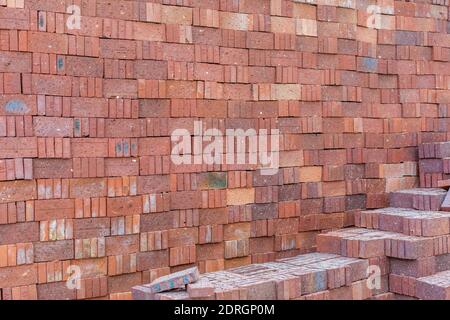 Rote Ziegelsteine stapelten sich in die Wand, bereit für den Bau Stockfoto