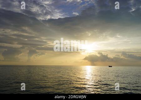 Sonnenuntergang über dem Meer, kleines Boot in der Ferne Stockfoto