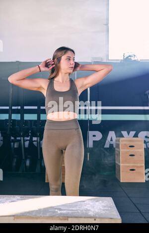 Fit junge Frau Box springen in einem Crossfit-Stil auf grauem Hintergrund. Fitness, Functional, Training und Lifestyle-Konzept Stockfoto