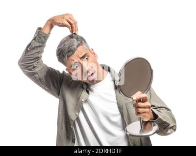 Gestresster Mann mit grauem Haar in Spiegel auf weiß Hintergrund Stockfoto