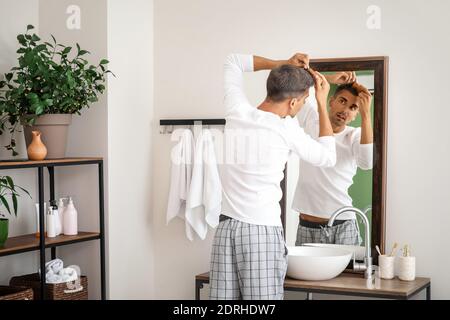 Gestresster Mann mit grauem Haar, der in den Spiegel schaut Stockfoto