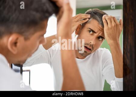 Gestresster Mann mit grauem Haar, der in den Spiegel schaut Stockfoto