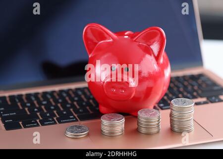 Rotes Sparschwein und Münzen auf der Laptop-Tastatur Stockfoto