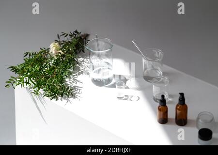 Heller kosmetischer Hintergrund. Fläschchen, Laborflaschen aus Glas auf dem Tisch. Naturkosmetik-Konzept. Stockfoto