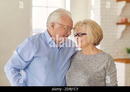 Der alte Mann und die alte Frau umarmen sich und genießen die gemeinsame Zeit zu Hause. Stockfoto