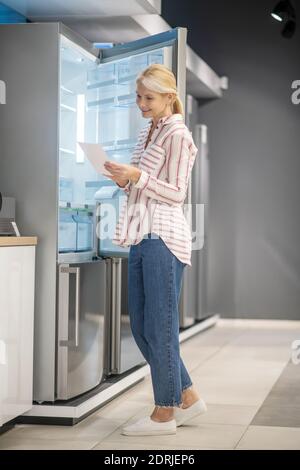 Blonde hübsche Frau wählte einen Kühlschrank in einem Showroom Stockfoto