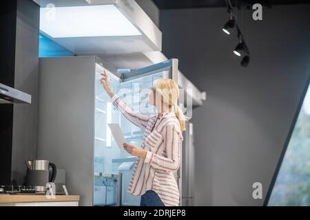 Blonde hübsche Frau wählte einen Kühlschrank in einem Showroom Stockfoto