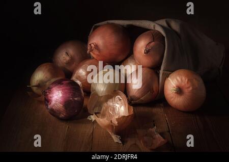 Zwiebeln in einem Stoffbeutel auf dunklem Holzhintergrund Stockfoto