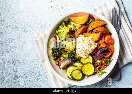 Gebackenes Gemüse mit Hummusschale. Salat mit gebackenen Süßkartoffeln, Zucchini, Brokkoli und Hummus. Veganes Lebensmittelkonzept. Stockfoto