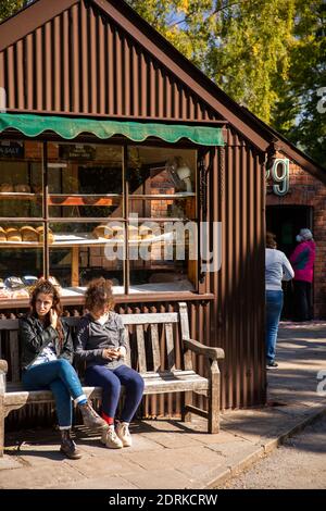 Großbritannien, Wales, Cardiff, St Fagans, National Museum of History, die Besucher saßen in Sonnenschein außerhalb Wellblech-Sattler-Werkstatt als Bäcker-Shop verwendet Stockfoto