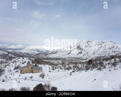 Verschneite Chimgan Berge, ein einsames Haus steht im Winter zwischen den Bergen Stockfoto