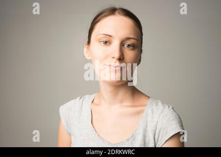 Ziemlich lächelnd freudig weiblich mit starken Haaren, lässig gekleidet, mit Zufriedenheit auf die Kamera schauen, glücklich sein. Studioaufnahme eines schönen Be Stockfoto