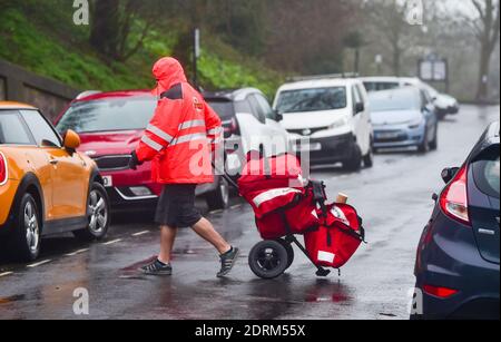 Brighton UK 21. Dezember 2020 - EIN Postbote liefert Weihnachtspost und Pakete in Brighton immer noch seine Shorts trotz der regen und Wind heute : Credit Simon Dack / Alamy Live News Stockfoto