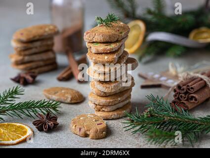 Gestapelte würzige Butterkekse mit kandierten Früchten, Zimtstangen und Anis. Festliche Weihnachten oder Neujahr Hintergrund mit Tannenzweigen und getrockneten oran Stockfoto