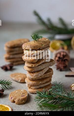 Gestapelte würzige Butterkekse mit kandierten Früchten, Zimtstangen und Anis. Festliche Weihnachten oder Neujahr Hintergrund mit Tannenzweigen und getrockneten oran Stockfoto