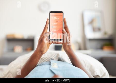 POV der jungen afroamerikanischen Frau hält Smartphone im Bett, während Musik am Morgen hören, kopieren Raum Stockfoto