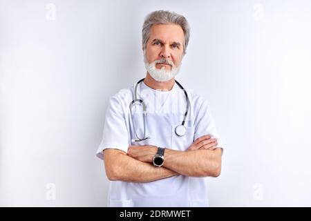 Selbstbewusst ältere männliche Arzt in weißen medizinischen Uniform mit Stethoskop, schaut auf Kamera posiert, isoliert auf weißem Hintergrund. Medizin Konzept Stockfoto