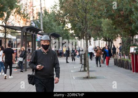 BELGRAD, SERBIEN - 10. OKTOBER 2020: Alter älterer Mann mit einem Hut, der eine Atemmaske trägt, der während des Coronavir in der Straße von Belgrad spazierend ist Stockfoto