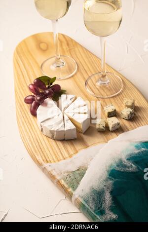 Gläser mit Wein und Käse auf einem Brett mit Nachahmung Von Meereswellen Stockfoto