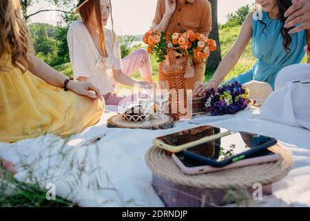 Digital Detox, Zeit zum Trennen von elektronischen Geräten. Handys auf Korb auf Picknick-Hintergrund. Eine Gruppe junger Frauen, die zusammen hingen Stockfoto