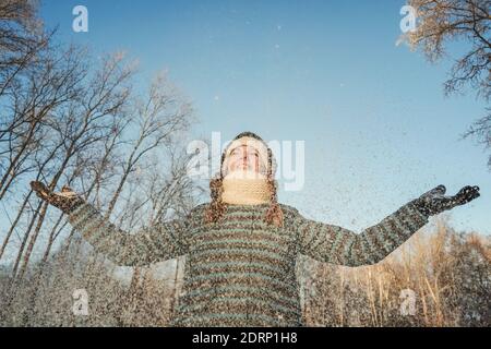 Glückliche Frau haben Spaß, spielen und werfen Schnee im Freien in der Winternatur. Schneefliege. Stockfoto