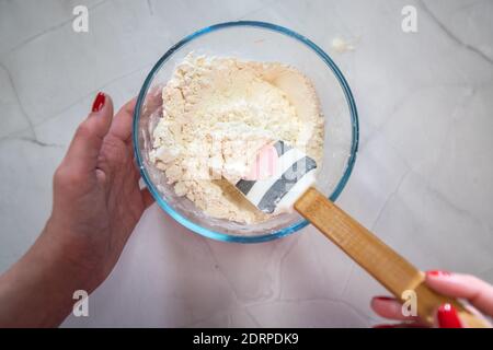 Frau Mischen Mehl in einer Glasschüssel auf weißem Hintergrund Stockfoto