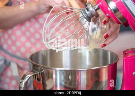 Weiße Frau in einer rosa Schürze mit großen Mixer Stockfoto