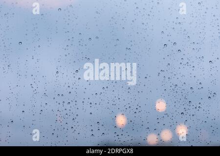 Ein mit Regentropfen bedecktes Fenster, ein nasses Fenster bei einem schweren Regenguss. Glasoberfläche Textur, große Tropfen Wasser, leerer Hintergrund für Design Stockfoto