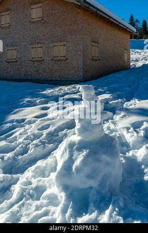 kleine Schneemänner auf einer Alp. almhütte mit Schneemanen. Winterlicht auf einem Almhof. Verschneite Landschaft in den Bergen Vorarlbergs Stockfoto