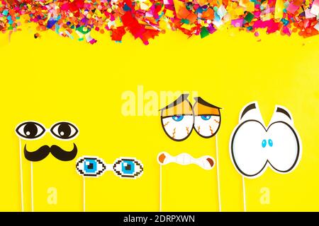 Zubehör für eine Party. Verschiedene Formen von lustigen Augen auf einem gelben Hintergrund. Party- und Karnevalskonzept. Speicherplatz kopieren. Stockfoto