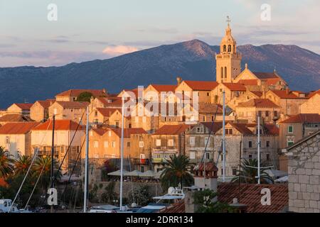 Korčula Stadt, Korčula, Dubrovnik-Neretva, Kroatien. Blick über Dächer auf die Altstadt, Sonnenuntergang, Berge der Halbinsel Pelješac dahinter. Stockfoto