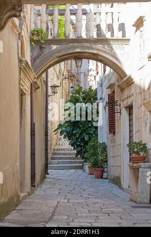 Korčula Stadt, Korčula, Dubrovnik-Neretva, Kroatien. Blick durch den Bogen auf die typische gepflasterte Straße im Herzen der Altstadt. Stockfoto