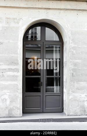 Neue gewölbte graue Holzdoppelflügeltür. Holztor - Eingang. Vintage alte graue Tür in Steinmauer in Betonhaus Paris Frankreich Stockfoto