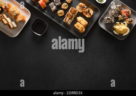 Asiatische Küche mit Sushi-Set auf schwarzem Hintergrund. Blick von oben. Flach liegend. Lieferung von Lebensmitteln. Stockfoto