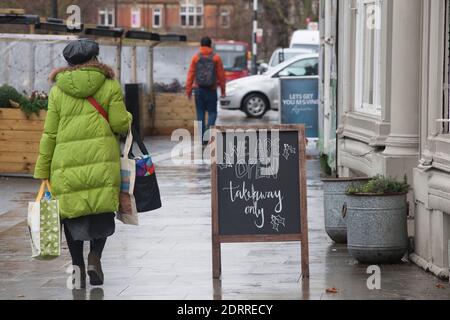 Clapham, London, 21. Dezember 2020: Im Regen stehen die Leute Schlange, um Weihnachtsaufträge von einem lokalen Metzger zu sammeln. Unter Tier 4 Coronavirus Einschränkungen sollten die Menschen zu Hause bleiben, außer für wesentliche Einkäufe und zur Arbeit zu gehen. Cafés und Restaurants sind nur für Essen zum Mitnehmen geöffnet und Deliveroo liefert Lebensmittel sowie warme Mahlzeiten. Anna Watson/Alamy Live News Stockfoto