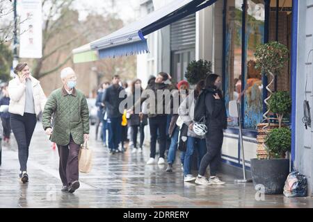 Clapham, London, 21. Dezember 2020: Im Regen stehen die Leute Schlange, um Weihnachtsaufträge von einem lokalen Metzger zu sammeln. Unter Tier 4 Coronavirus Einschränkungen sollten die Menschen zu Hause bleiben, außer für wesentliche Einkäufe und zur Arbeit zu gehen. Cafés und Restaurants sind nur für Essen zum Mitnehmen geöffnet und Deliveroo liefert Lebensmittel sowie warme Mahlzeiten. Anna Watson/Alamy Live News Stockfoto