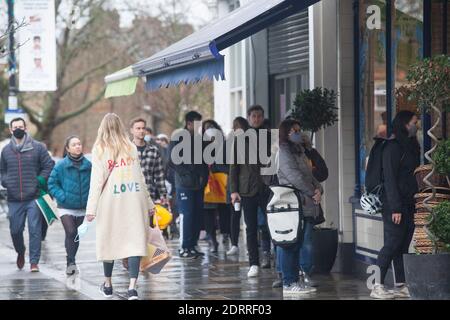 Clapham, London, 21. Dezember 2020: Im Regen stehen die Leute Schlange, um Weihnachtsaufträge von einem lokalen Metzger zu sammeln. Unter Tier 4 Coronavirus Einschränkungen sollten die Menschen zu Hause bleiben, außer für wesentliche Einkäufe und zur Arbeit zu gehen. Cafés und Restaurants sind nur für Essen zum Mitnehmen geöffnet und Deliveroo liefert Lebensmittel sowie warme Mahlzeiten. Anna Watson/Alamy Live News Stockfoto