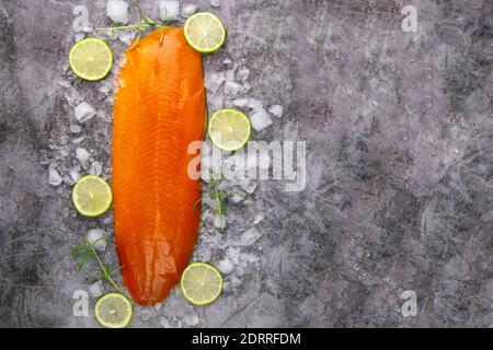 Frisches, rohes Lachsfischsteak mit Gewürzen auf Eis auf dunklem Steingrund. Kreatives Layout aus Fisch, Draufsicht, flache Lage mit Freiraum Stockfoto