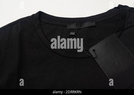 Leeres Etikett und Etikett auf einem schwarzen Baumwoll-T-Shirt. Nahaufnahme Stockfoto