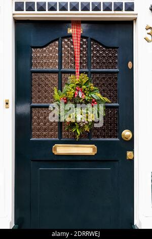 Vintage-Vordertür mit festlichem Dekor Weihnachtskranz auf rotem Band dekoriert. Traditionelle Weihnachten europäischen Exterieur in den Niederlanden Stockfoto